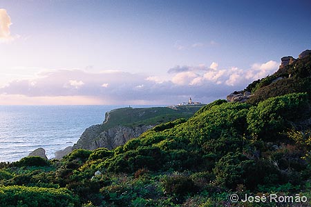x06314B O Cabo da Roca - o ponto mais ocidental da Europa continental - e farol, vistos do Espinha�o, a sul, ao fim da tarde. costa fal�sia mar arbustos verde Parque-Natural-Sintra-Cascais